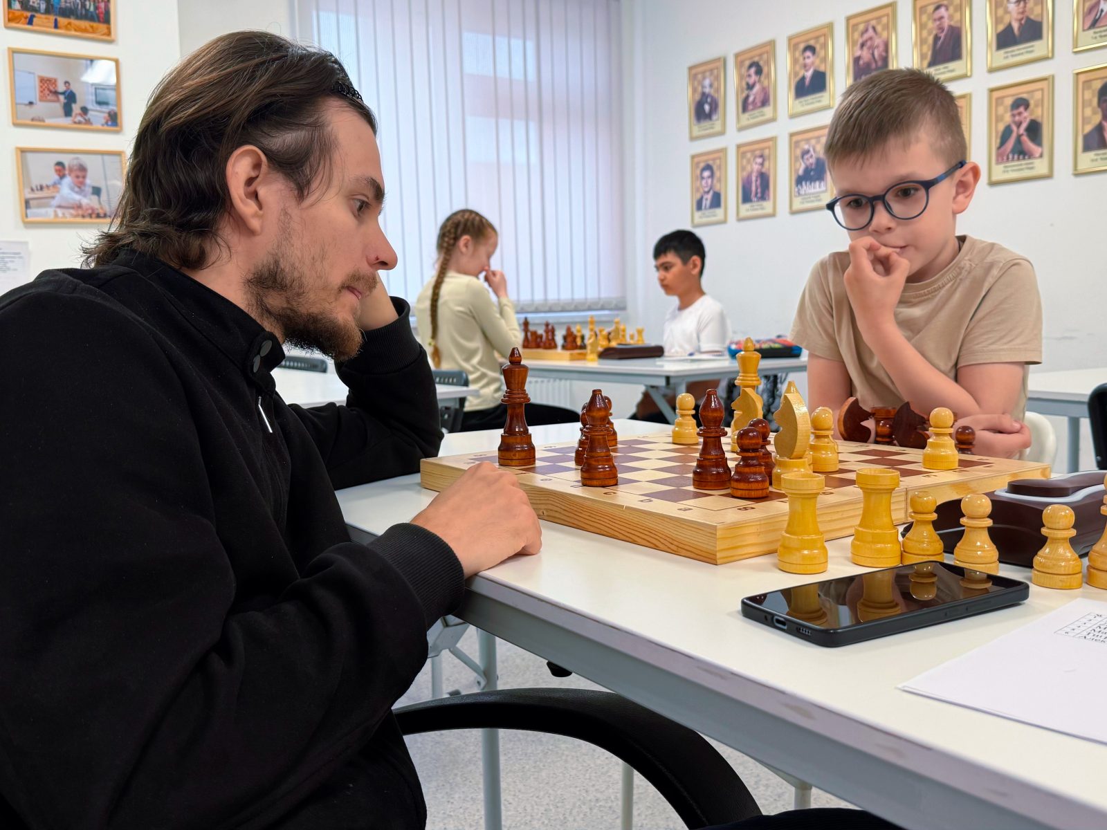 Занятие в шахматной школе «Ход Конём» Тренер играет в шахматы с учеником в школе «Ход Конём» в Екатеринбурге